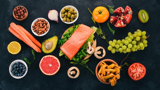 石のテーブルの上の健康食品のセット魚野菜果物ナッツベリーキノコ上面図テキスト用の空きスペース