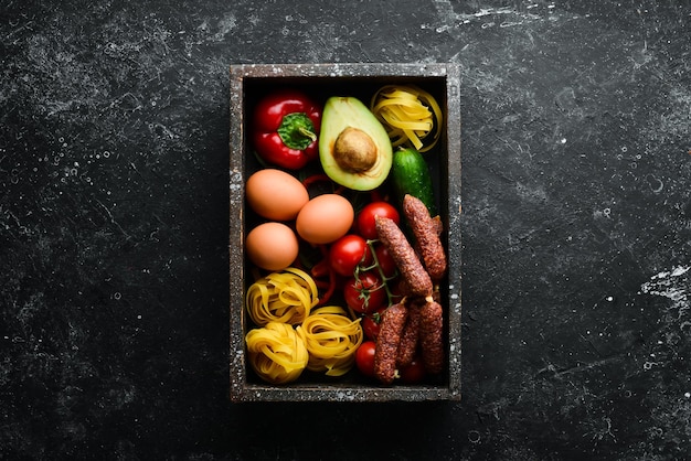 Set of healthy food tomatoes pasta spices vegetables and sausages Top view Black stone background