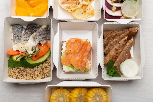 Set of healthy meals for the day in lunch boxes stands on a white table.