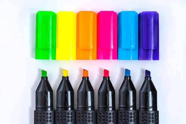 Set of highlighter markers sorted by color aligned and uncovered on white background. Foreground.