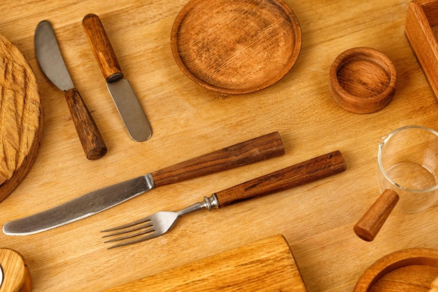 Set houten bestek houten keukengerei en keukengerei op tafel Bovenaanzicht Houten messen en vork en bord