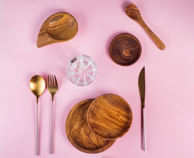 Set houten keukengerei gemaakt van olijfhout met luxe gouden bestek op roze, plat leggen