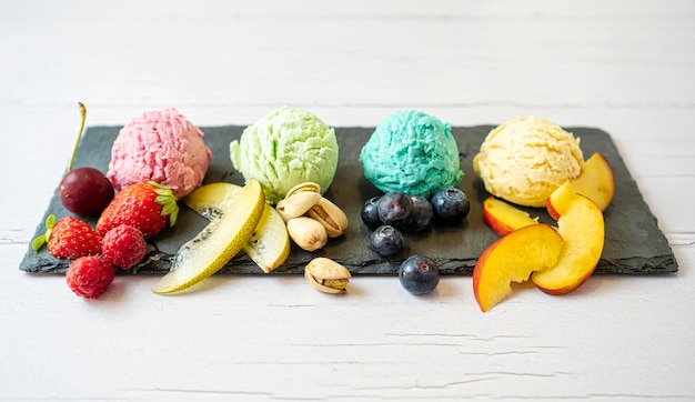 Set of ice cream scoops of different colors and flavours with berries nuts and fruits decoration