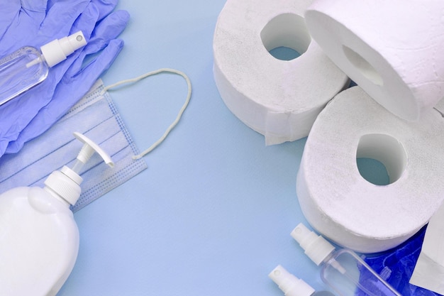 Набор важных предметов для карантина Covid19 Резиновые одноразовые перчатки из туалетной бумаги с хирургической маской для лица и дезинфицирующим средством для рук с бутылкой с жидким мылом на синем фоне