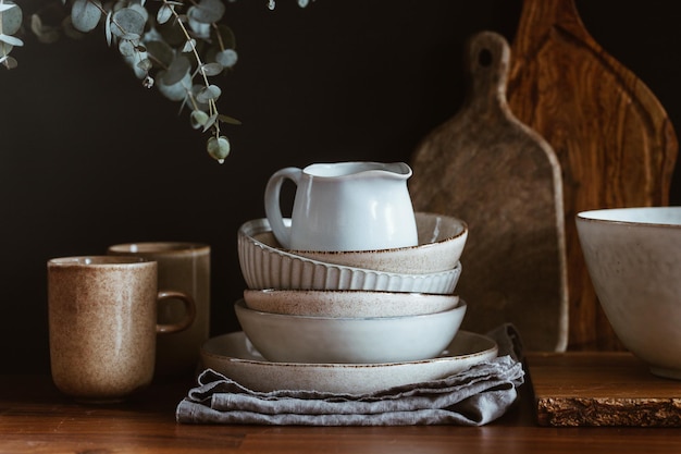 Set of kitchen ceramic tableware and wooden cutting boards on a table Eco style home still life