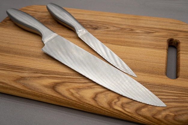 Set of kitchen knives and cutting board on a gray background Two gray kitchen knives