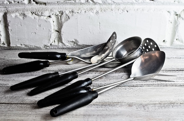 Un set di utensili da cucina per cucinare contro un muro di mattoni bianchi.