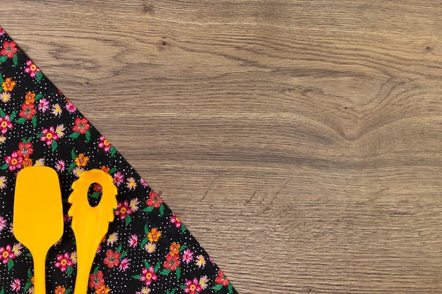 Set of kitchen utensils. Floral tablecloth on wooden background.