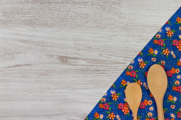 Set of kitchen utensils. Floral tablecloth on wooden background.