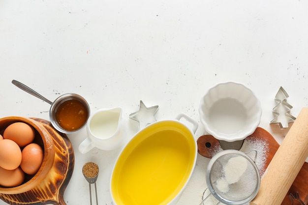 Set of kitchen utensils and ingredients for preparing bakery on light background