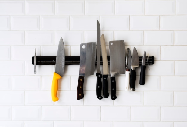 Photo set of knifes hanging on the white wall