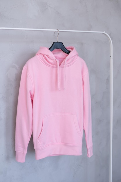 A set of layouts of a pink hoodie with a hood and a pocket hanging on a hanger