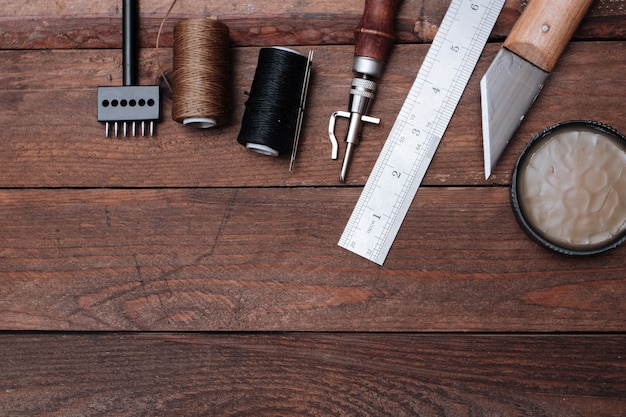 Photo set of leather crafting tools. shoes maker tools on wooden table.