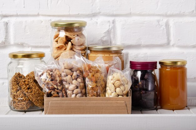 Set of long storage term mostly dry sweet energy foods on\
pantry shelf on brick wall background