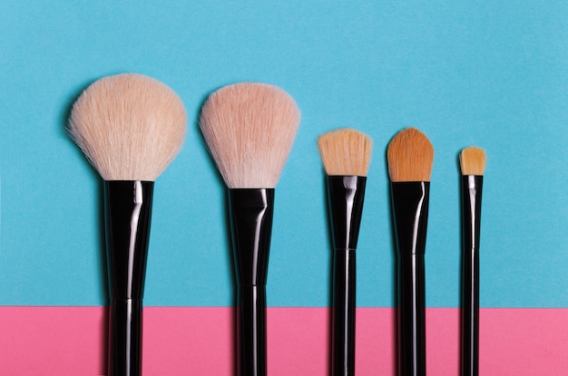 Set of makeup brushes on blue background.