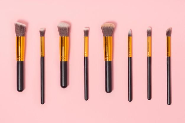 Set of makeup brushes on pink background