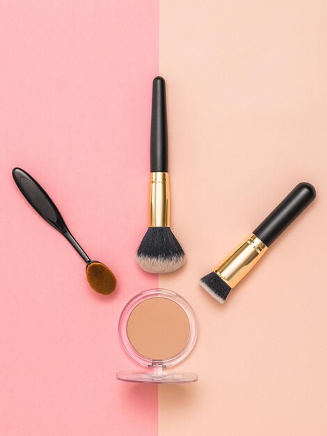 A set of makeup brushes and powder on a twocolor background Makeup device