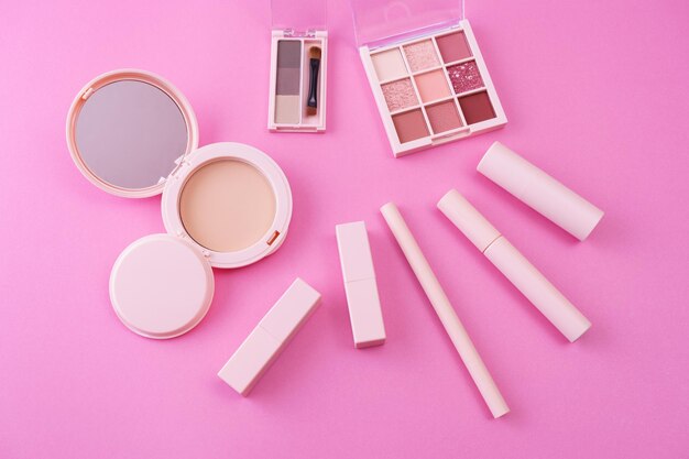 A set of makeup tools placed on a pink background