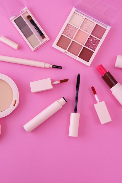 A set of makeup tools placed on a pink background