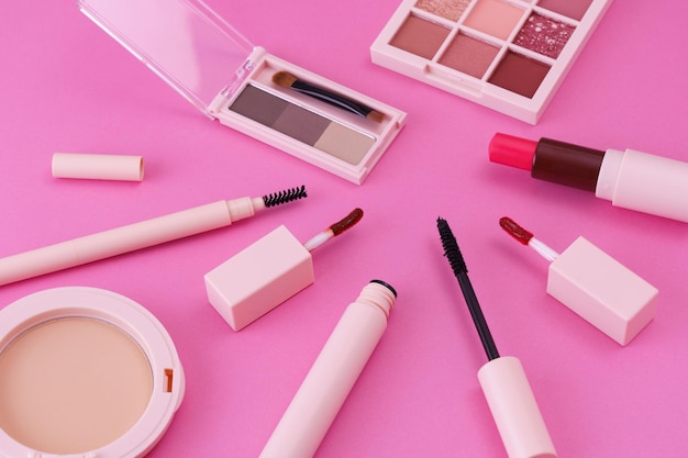 A set of makeup tools placed on a pink background