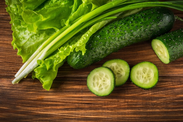 Impostare per fare un'insalata di erbe fresche, cetrioli e cipolle sul tavolo vintage