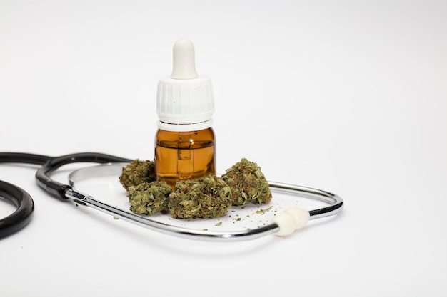 set of marijuana buds with dosing bottle stethoscope white background