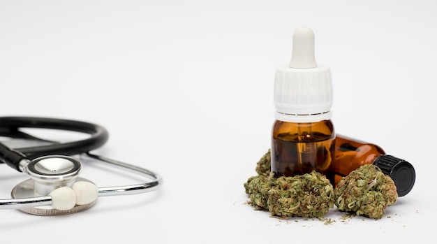 set of marijuana buds with dosing bottle stethoscope white background