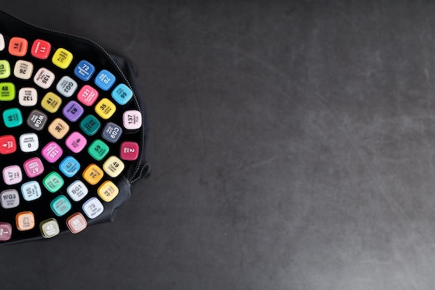 A set of markers for drawing in different colors for sketching with markings in a bag on a black background.