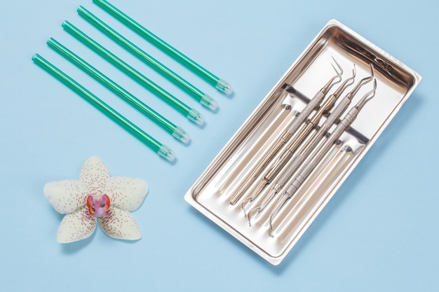 Set of metal dental instruments for dental treatment and saliva ejectors. Medical tools in stainless steel tray.