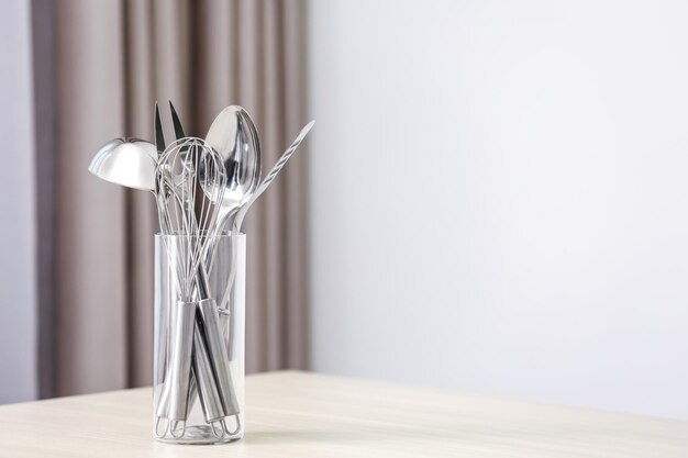 Set of metal kitchen utensils in glass on table