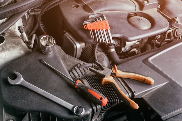 Premium Photo  A set of metal spanners, screwdrivers, pliers and ratchet  of different sizes lies under the hood of the car on an oil cooler. concept  of car repair and tools