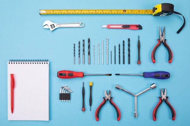 Photo set of metalwork tools with notebook and pen on colorful