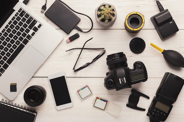 Set of modern photographic equipment on white wooden table, top view. Professional tools of creative designer, photographer workplace background