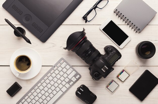 Set of modern photographic equipment on white wooden table, top view. Professional tools of creative designer, photographer workplace background