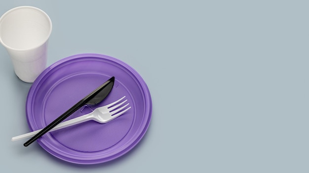 A set of multi-colored plastic utensils on a gray background, top view. Plastic recycling.