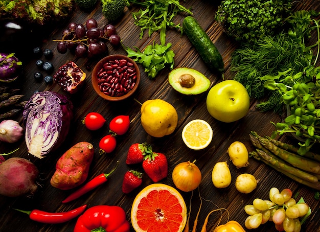 Set of multicolor fresh organic vegetables and fruits laying on dark wooden surface Large assortment of vegan products