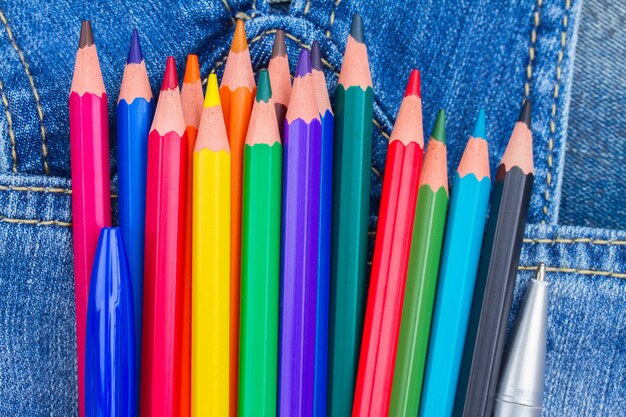 Photo set of multicolored pencils in blue jeans pocket close up