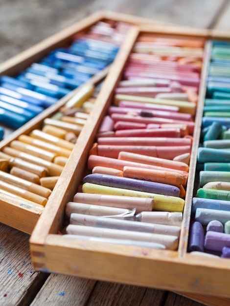 Set of multicolored professional artistic pastel crayons in open wooden box on table Selective focus