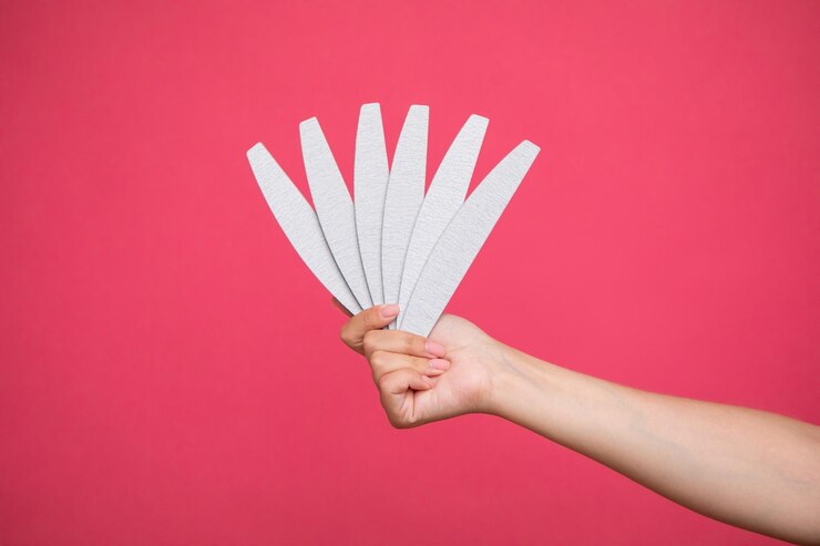 ピンクの背景に女性の手の爪やすりのセット。ネイリスト機器