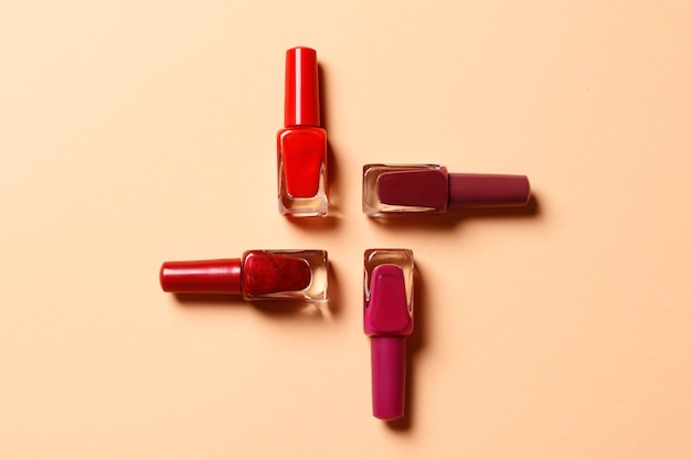 set of nail polish on coral background. place for text. top view.