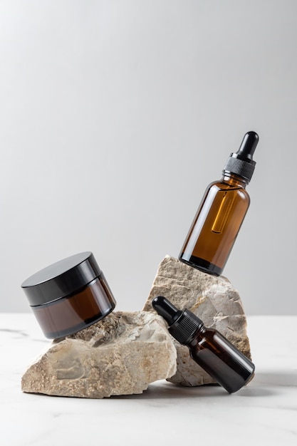 Set natural beauty cosmetic skincare products in glass bottles on stone pedestal balancing rock pile