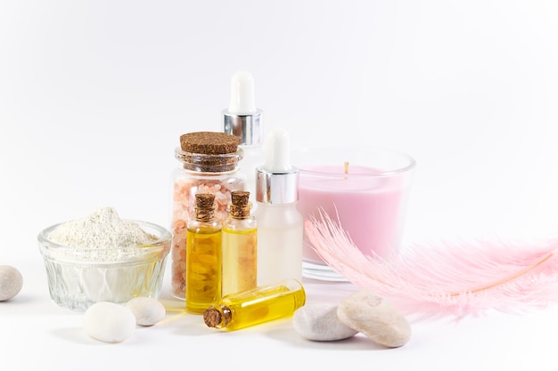 Foto set di prodotti cosmetici naturali come sieri oli cosmetici argilla candele aromatiche e pietre da massaggio su sfondo bianco