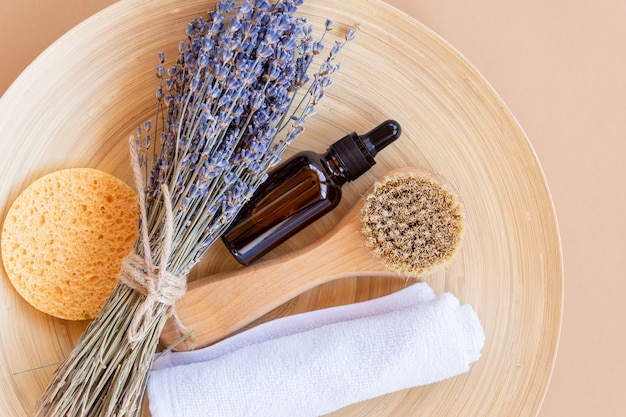 Set of natural organic cosmetics with lavender essential oil and bathroom accessories on a bamboo plate. Sustainable consumption