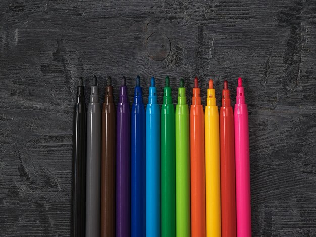 A set of neatly stacked colored markers on a wooden background. Universal markers for school and office.