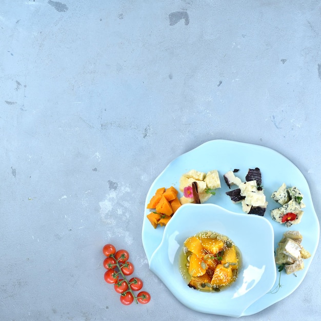 A set of noble cheeses - parmesan, dor blue, roquefort, gorgonzola on a round plate with jam