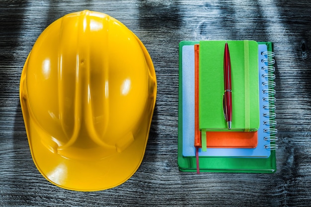 Set of notebooks pen safety hard hat on wooden board