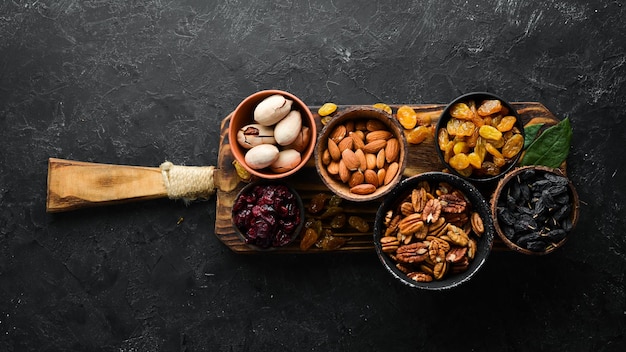 Set of nuts and dried fruits and berries on a black stone background Top view Free space for your text