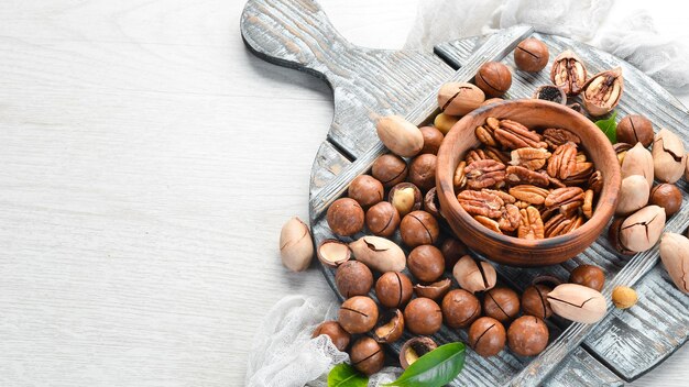 Set of nuts. pecans and macadamia nuts in bowls on a white background. Top view. Free space for your text.