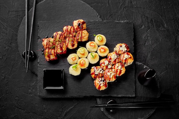 Фото Набор запеченных суши-роллов на двоих с соевым соусом на грифельной доске