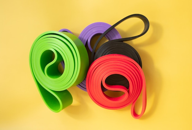 Фото Набор ярких многоцветных резиновых лент для фитнеса на желтом фоне